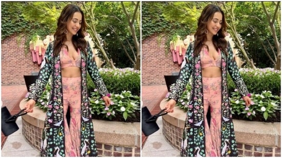 Rakul Preet teamed a pink floral cropped top with a plunging neckline with a pair of pink sharara set that came intricately detailed in miniature floral patterns. She added more drama to her look with a black long shrug with multicoloured patterns.(Instagram/@rakulpreet)