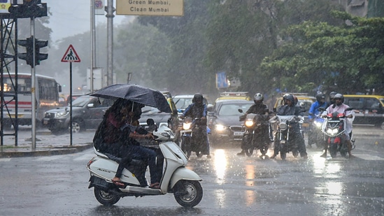 Commuters move on a road amid monsoon rains, in Mumbai.(PTI)