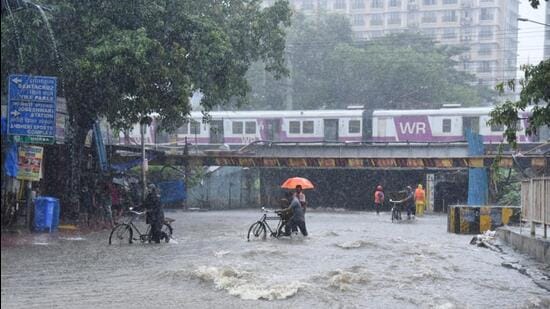 People walk in a waterlogged road near Andheri Subway at Andheri in Mumbai. (HT photo | Vijay Bate)