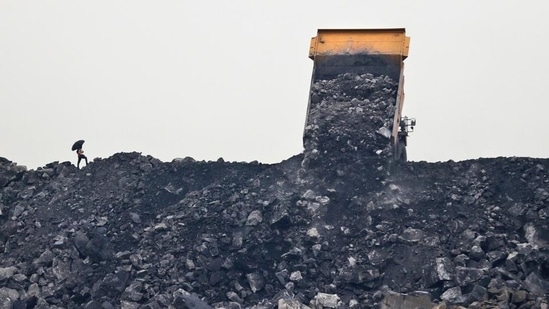 A worker keeps watch as a truck unloads coal in the village of Rajapur.