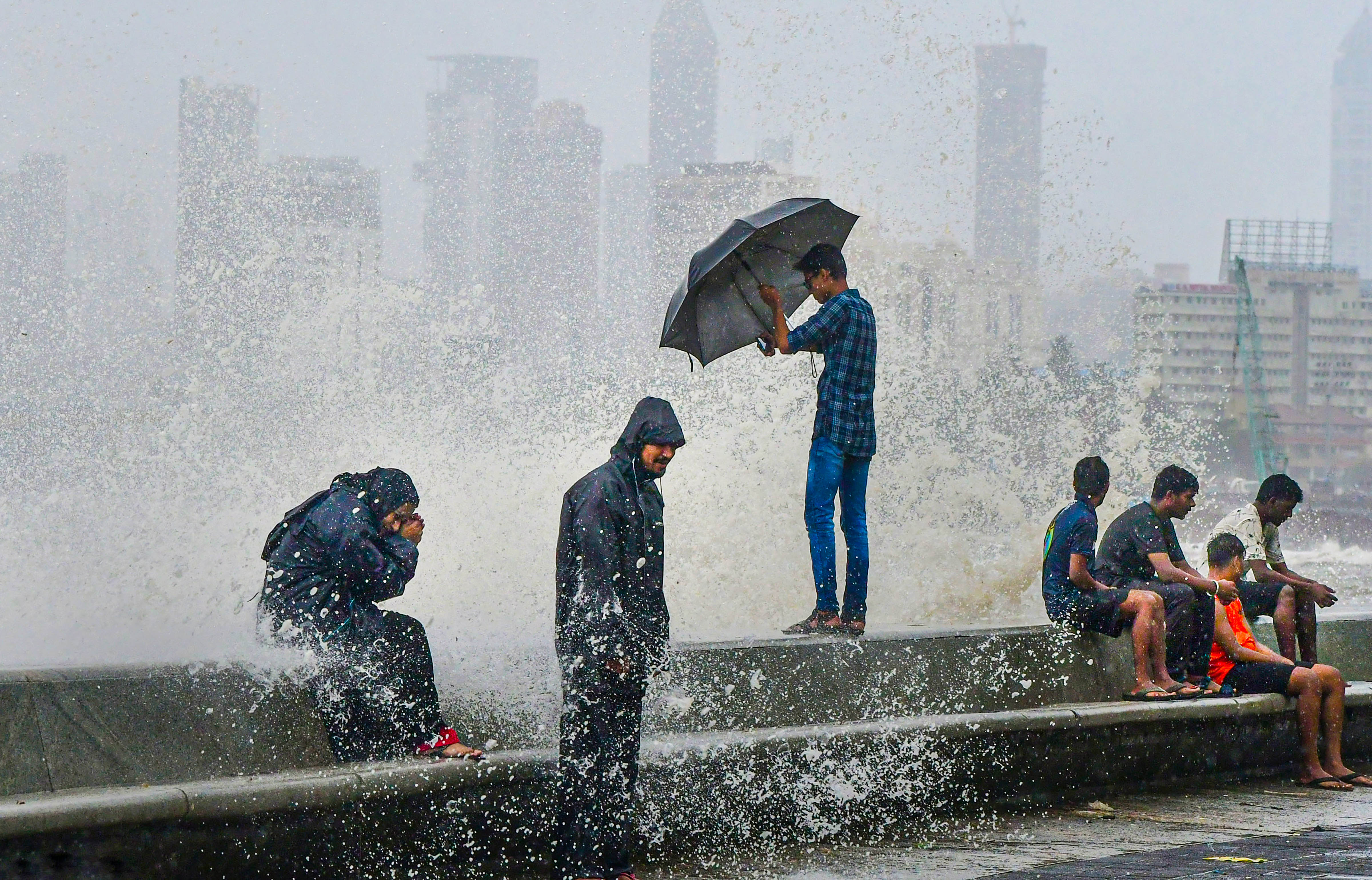 People sit along the Marine Drive in Mumbai on Tuesday. (PTI) People sit along the Marine Drive in Mumbai on Tuesday. (PTI)