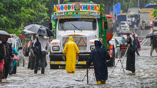 Commuters wade through a waterlogged road following monsoon rain, in Mumbai, on July 5, 2022. (PTI) Commuters wade through a waterlogged road following monsoon rain, in Mumbai, on July 5, 2022. 