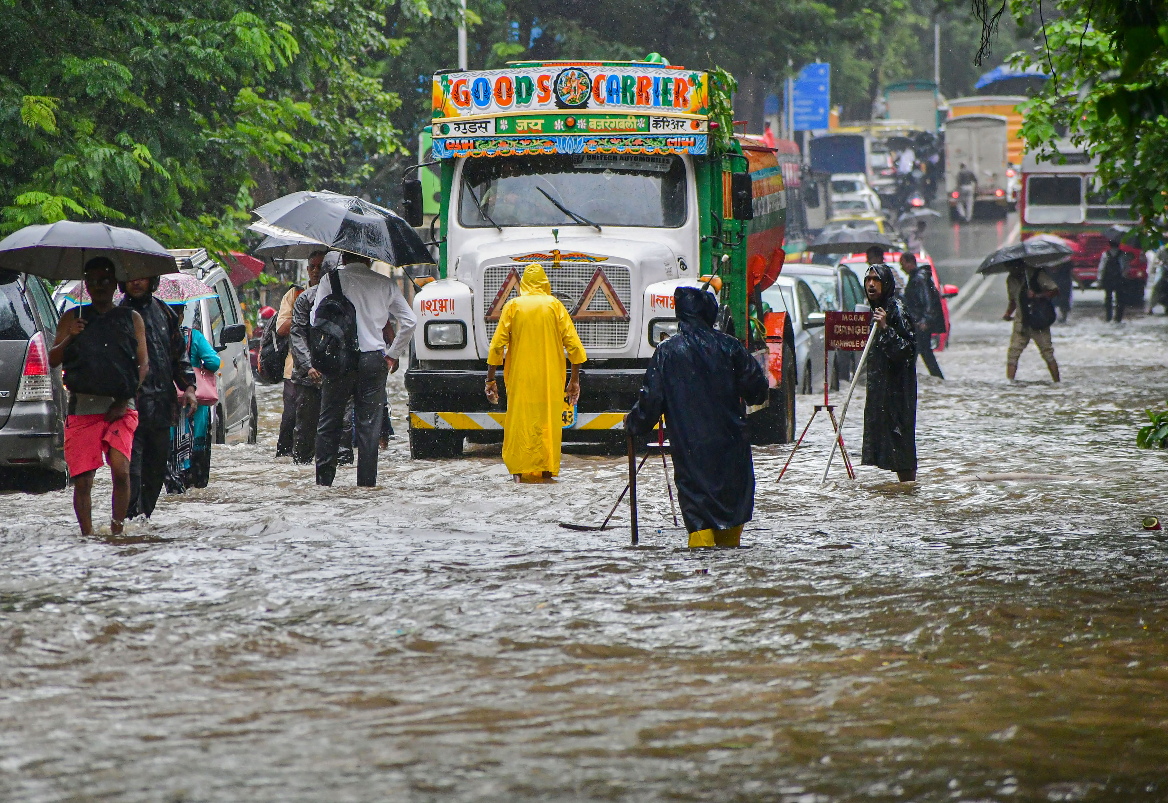 Commuters wade through a waterlogged road following monsoon rain, in Mumbai, on July 5, 2022. (PTI)