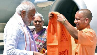 Uttar Pradesh chief minister Yogi Adityanath welcomes Prime Minister Narendra Modi on his arrival in Varanasi as governor Anandiben Patel looks on. (ANI PHOTO)