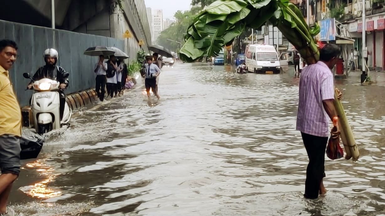 People wade through waterlogged road amid heavy rainfall, at Khodadad Circle, Dadar , in Mumbai on July 6, 2022. (ANI Photo)