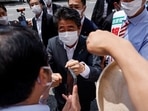 Former Japanese prime minister and ruling Liberal Democratic Party lawmaker Shinzo Abe bumps fists with voters.