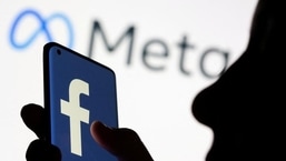 Mulher segura smartphone com o logotipo do Facebook na frente de um novo logotipo de rebrand do Facebook exibido Meta nesta imagem de ilustração (Foto de arquivo REUTERS)