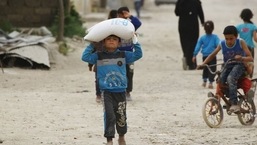 A boy carries food aid given by UN's World Food Programme in Raqqa, Syria.