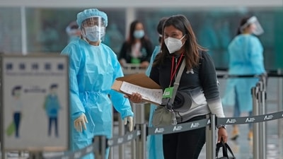 Workers wearing protective gear direct arriving passengers to quarantine hotels in the Hong Kong International Airport. Hong Kong is shelving a Covid-19 measure that has resulted in dozens of cancelled flights in recent months and thwarted travel plans for thousands. (AP Photo/Kin Cheung ) Workers wearing protective gear direct arriving passengers to quarantine hotels in the Hong Kong International Airport. Hong Kong is shelving a Covid-19 measure that has resulted in dozens of cancelled flights in recent months and thwarted travel plans for thousands. (AP Photo/Kin Cheung )