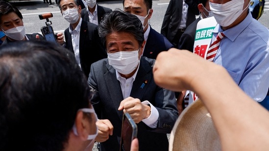 FILE PHOTO: Former Japanese prime minister and ruling Liberal Democratic Party lawmaker Shinzo Abe bumps fists with voters.