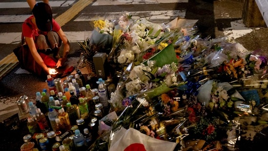 A person pays respects next to tributes laid at the site where Shinzo Abe was shot while campaigning for a parliamentary election, near Yamato-Saidaiji station in Nara.&nbsp;(Reuters)