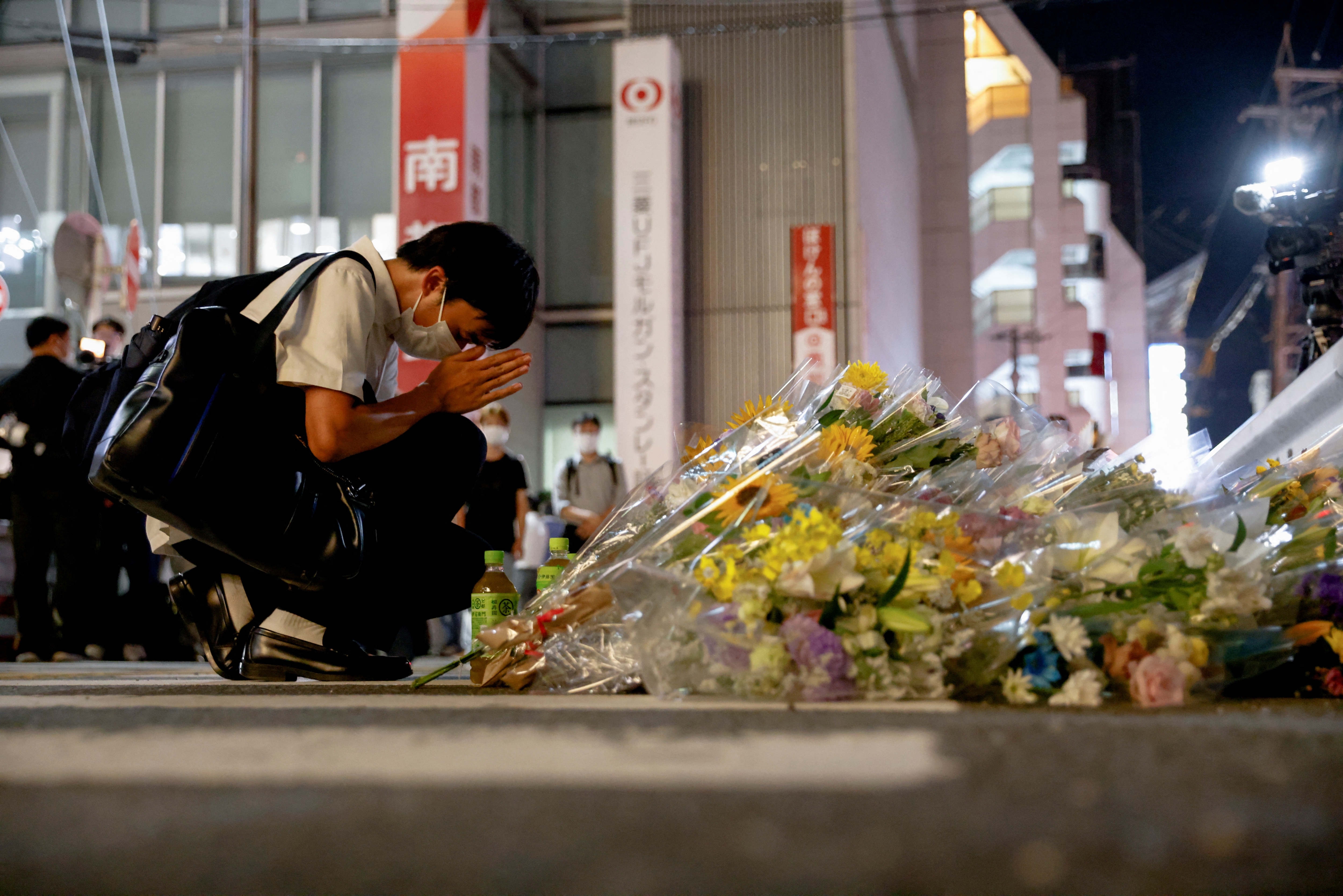 A person prays next to flowers laid at the site where late former Japanese PM Shinzo Abe was shot in Nara, western Japan. REUTERS/Issei Kato