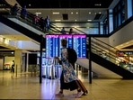 A passenger walks past a digital billboard displaying departing flights at Berlin Brandenburg International airport. A passenger walks past a digital billboard displaying departing flights at Berlin Brandenburg International airport. 
