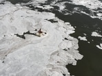 A man rides a makeshift boat through toxic foam floating in Yamuna river in New Delhi. A man rides a makeshift boat through toxic foam floating in Yamuna river in New Delhi.
