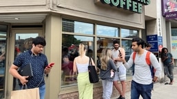 People crowd around a Starbucks coffee shop to use its free wifi on the Bell network, during a major outage of Rogers Communications' mobile and internet networks.