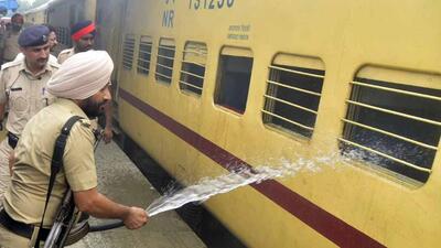 A policeman using a hose to douse the fire in a train stationed at Platform 5 of the Ludhiana Railway Station on Saturday. (Gurpreet Singh/HT)