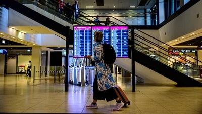 A passenger walks past a digital billboard displaying departing flights at Berlin Brandenburg International airport.&nbsp; (AFP)