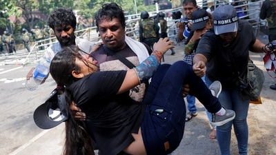 A demonstrator carries an injured woman near President's residence after riot police used tear gas to disperse demonstrators in Colombo. (REUTERS)