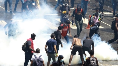 Protesters try to remove a tear gas shell after it was fired by police to disperse them in Colombo, Sri Lanka, Saturday. (AP) Protesters try to remove a tear gas shell after it was fired by police to disperse them in Colombo, Sri Lanka, Saturday. (AP)
