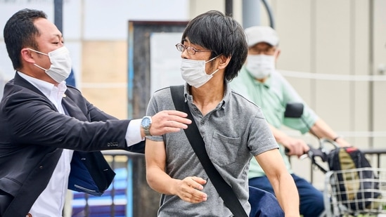 Tetsuya Yamagami, center, holding a weapon, is detained near the site of gunshots in Nara, western Japan Friday, July 8, 2022 .(Nara Shimbun/Kyodo News via AP)