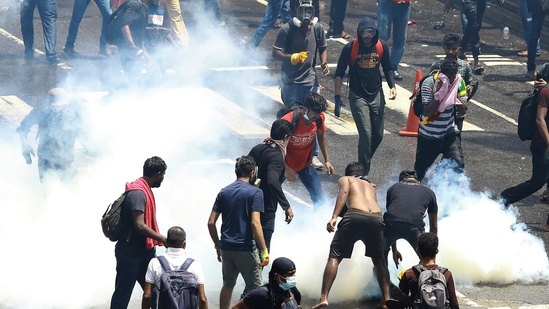 Protesters try to remove a tear gas shell after it was fired by police to disperse them in Colombo, Sri Lanka, Saturday.&nbsp;(AP)