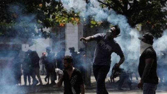 A demonstrator throws back a tear gas grenade towards police members as police use tear gas and water cannons to disperse demonstrators during a protest demanding the resignation of President Gotabaya Rajapaksa.&nbsp;(via Reuters)