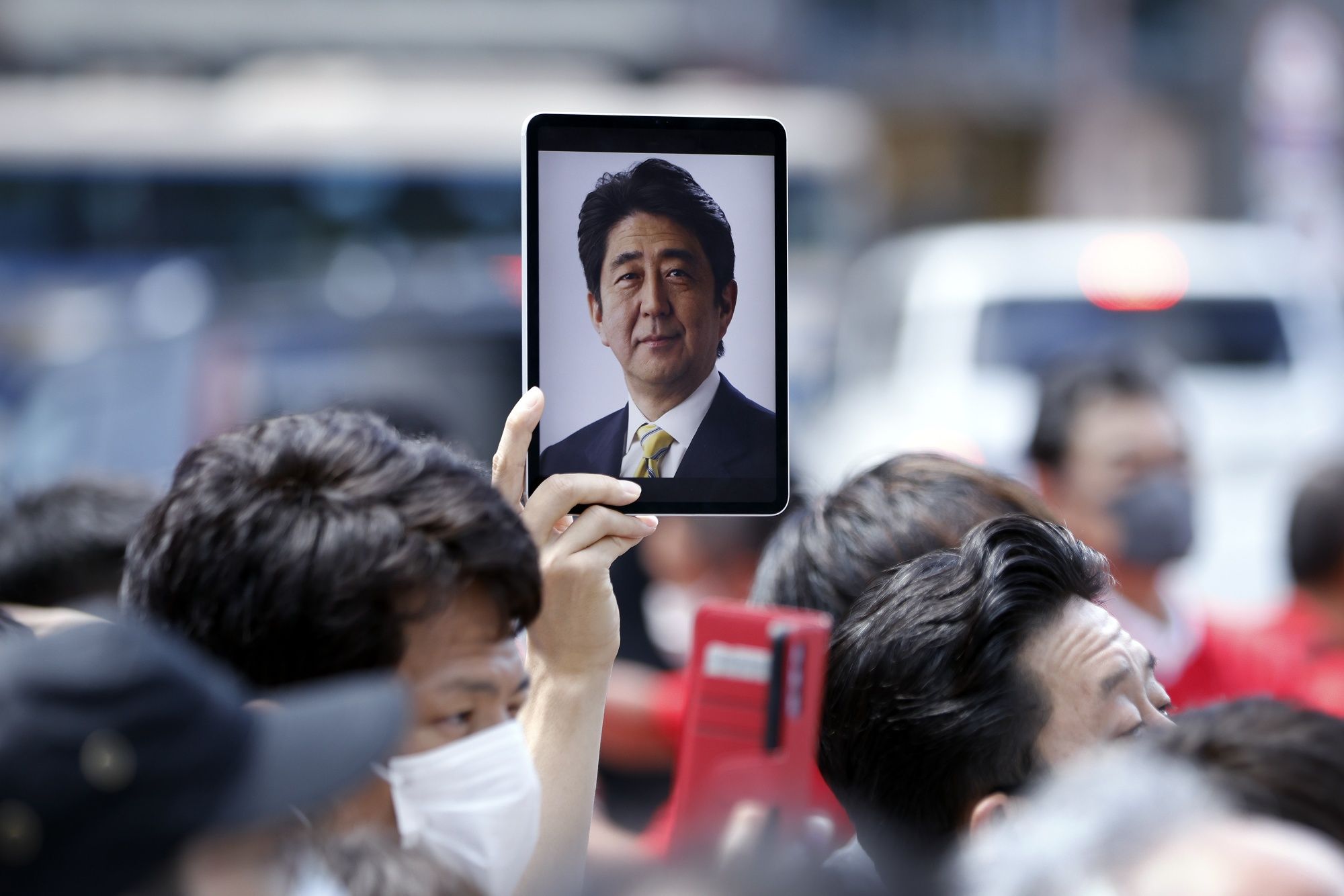 An attendee holds a tablet computer displaying a photograph of former Japanese Prime Minister Shinzo Abe during an election campaign event in Yokohama, Japan, on Saturday, (Photographer: Kiyoshi Ota/Bloomberg) An attendee holds a tablet computer displaying a photograph of former Japanese Prime Minister Shinzo Abe during an election campaign event in Yokohama, Japan, on Saturday, (Photographer: Kiyoshi Ota/Bloomberg)