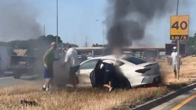 The image, taken from the Twitter video, shows a few men trying to save the driver from a burning car. (Twitter/@OPP_HSD)