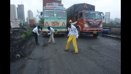 Traffic police filling potholes on a major road in Thane. (PRAFUL GANGURDE/HT PHOTO)