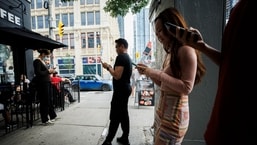 People use electronic devices outside a cafe in Toronto amid a nationwide Rogers outage, affecting many of the telecommunications company's services.