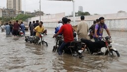 I residenti percorrono una strada allagata durante la stagione dei monsoni a Karachi, in Pakistan.