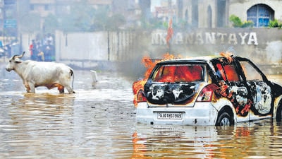 A cow moves past a burning car that, according to fire officials, caught fire by an electrical short circuit after it was stuck in a water-logged road following heavy rains in Ahmedabad, India, July 11, 2022. REUTERS/Amit Dave TPX IMAGES OF THE DAY (REUTERS) A cow moves past a burning car that, according to fire officials, caught fire by an electrical short circuit after it was stuck in a water-logged road following heavy rains in Ahmedabad, India, July 11, 2022. REUTERS/Amit Dave TPX IMAGES OF THE DAY (REUTERS)