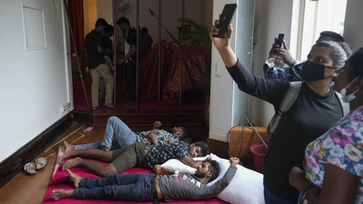 People take selfies as protestors sleep on the floor of President Gotabaya Rajapaksa's official residence. (AP) People take selfies as protestors sleep on the floor of President Gotabaya Rajapaksa's official residence. (AP)