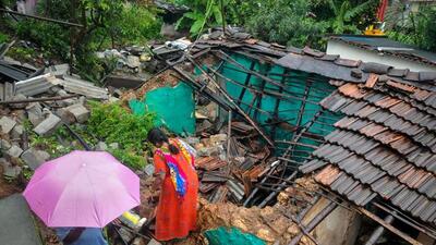Locals walk past a partially collapsed house, in Chikmagalur. (PTI)