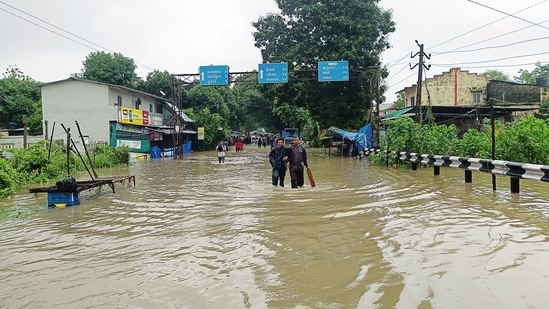 People wade through a waterlogged street after heavy rainfall, in Navsari in Gujarat.