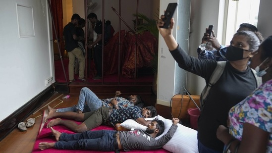 People take selfies as protestors sleep on the floor of President Gotabaya Rajapaksa's official residence.(AP)