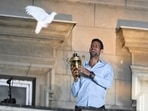 Serbian tennis player Novak Djokovic holds up the winner's trophy and greets fans during a welcoming ceremony in front of the city hall in Belgrade, in Serbia