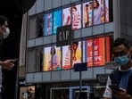 Pedestrians wearing protective masks walk past a Gap Inc. store in the Central district of Hong Kong.&nbsp;