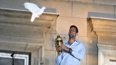 Serbian tennis player Novak Djokovic holds up the winner's trophy and greets fans during a welcoming ceremony in front of the city hall in Belgrade, in Serbia (REUTERS)