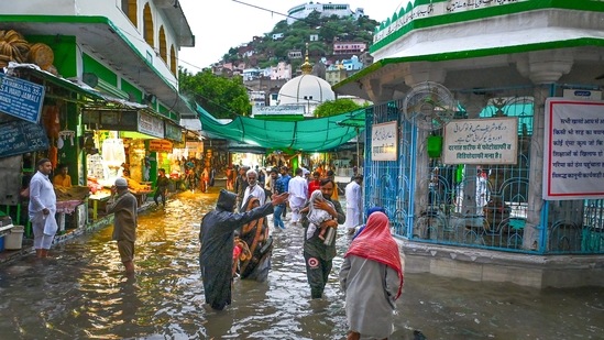 People wade through a waterlogged street after heavy rain in Rajasthan's Ajmer.(PTI)