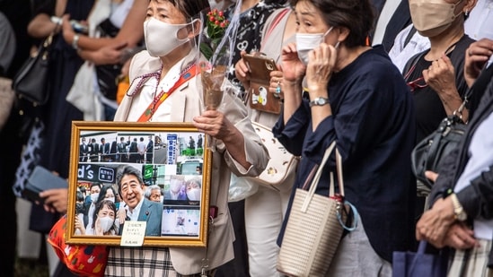 People gather for the hearse carrying late former Japanese prime minister Shinzo Abe leaves Zojoji Temple in Tokyo on July 12, 2022.(AFP)