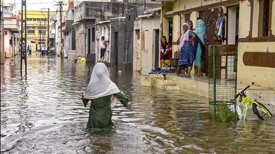 A young girl wades through a waterlogged street after rainfall in Rajkot, Gujarat on Tuesday. (PTI Photo) A young girl wades through a waterlogged street after rainfall in Rajkot, Gujarat on Tuesday. (PTI Photo)