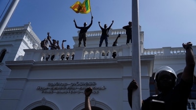 Sri Lankan protesters wave the national flag from the roof of prime minister Ranil Wickremesinghe 's office, demanding he resign after president Gotabaya Rajapaksa fled the country amid economic crisis in Colombo. (AP) Sri Lankan protesters wave the national flag from the roof of prime minister Ranil Wickremesinghe 's office, demanding he resign after president Gotabaya Rajapaksa fled the country amid economic crisis in Colombo. (AP)