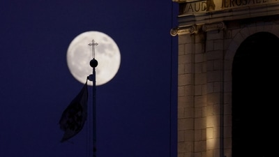 The waxing gibbous moon rises behind a cross at a church in the old city of JerusalemoOn July 12, 2022, a day ahead of the July "buck supermoon". (AFP) The waxing gibbous moon rises behind a cross at a church in the old city of JerusalemoOn July 12, 2022, a day ahead of the July "buck supermoon". (AFP)