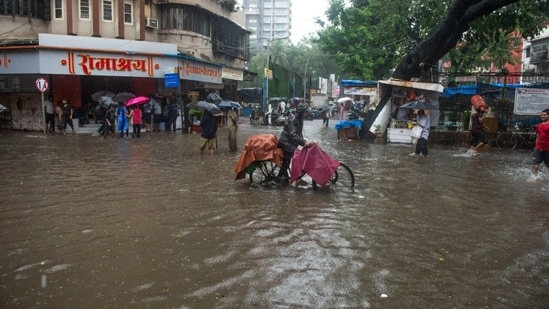 A man on a bicycle drive through water logged street outside Matunga Railway station(E) in Mumbai, India, on Wednesday, July 13, 2022.&nbsp;