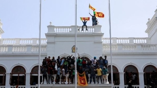 Protestors hold Sri Lankan flags as they stand on top of the office of Sri Lanka's Prime Minister Ranil Wickremesinghe, in Colombo.&nbsp;(Reuters)