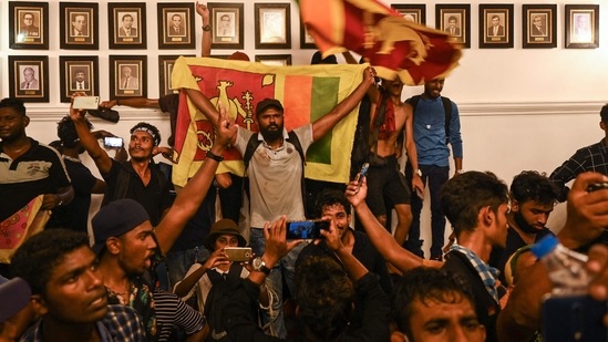 Demonstrators shout slogans and wave Sri Lanka flags inside the office building of Sri Lanka's prime minister during an anti-government protest in Colombo.(AFP)