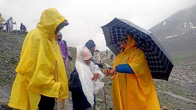 An MRT team helping Amarnath pilgrims with raincoats to protect them from rain on Thursday. (ANI)