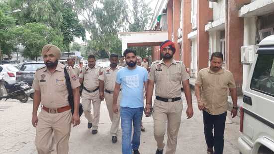 Gangster Gurdeep Singh alias Manna being accompanied by police at the Dera Bassi court complex on Thursday. (HT Photo)