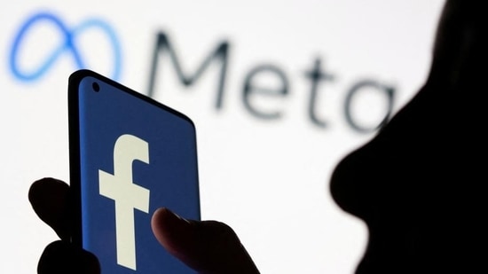 Woman holds smartphone with Facebook logo in front of a displayed Facebook's new rebrand logo Meta in this illustration picture (REUTERS File Photo)